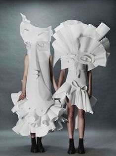 two models in white dresses made out of paper