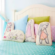 three pillows on top of a bed with cartoon drawings and polka dots in the comforter