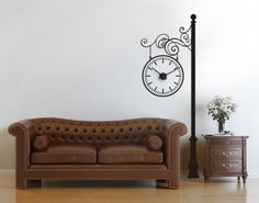 a brown leather couch sitting in front of a clock on a wall next to a lamp