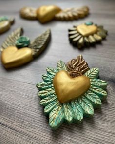 gold and green heart shaped brooches sitting on a table