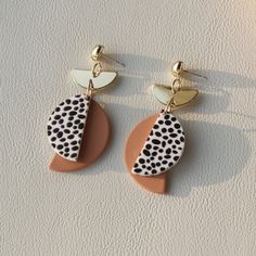 two pairs of earrings on top of a white surface, one with black and orange designs