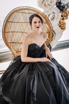 a woman in a black dress sitting on a chair