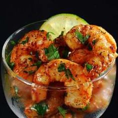 a glass bowl filled with cooked shrimp and garnished with parsley