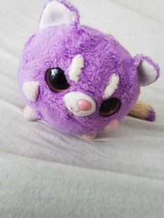 a purple stuffed animal laying on top of a bed