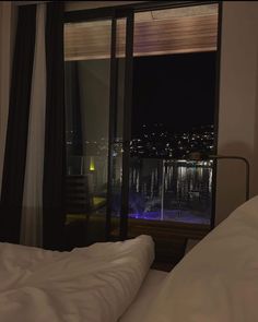 a bedroom with a view of the city at night from it's window sill