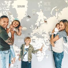 two adults and three children standing in front of a world map with animals on it