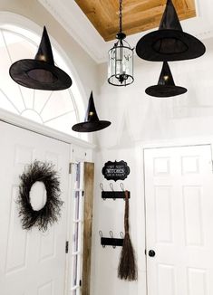 an entryway decorated for halloween with witches hats and brooms hanging from the ceiling