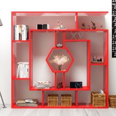 a red book shelf filled with books next to a lamp and wicker baskets on the floor