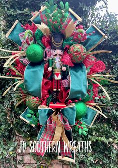 a christmas wreath is hanging on the side of a brick wall with green and red decorations