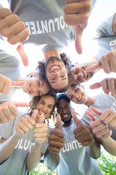 a group of people standing in a circle with their hands together and thumbs up to the camera