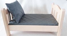 a small wooden bed with a blue pillow on it's headboard and foot board