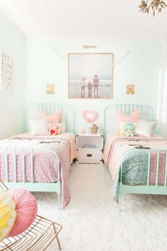 two beds in a room with pink and green decor