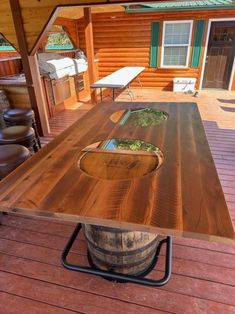 a wooden table sitting on top of a wooden deck next to a chair and bar