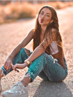 a young woman sitting on the ground with her tongue out and making a funny face