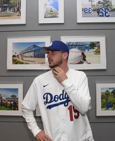 a man standing in front of a wall with pictures on it and holding his hand to his mouth