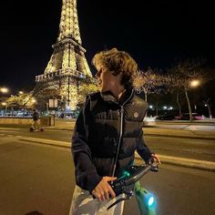 a young man standing next to a bike in front of the eiffel tower