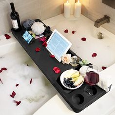 a bathtub filled with wine and food next to two candles on the edge of it