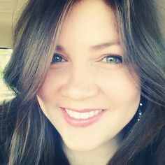 a close up of a person with long hair and blue eyes smiling at the camera