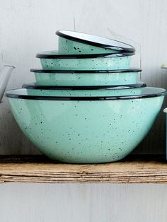 a stack of green bowls sitting on top of a wooden shelf