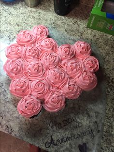 a heart shaped cupcake with pink frosting roses on the top is sitting on a counter