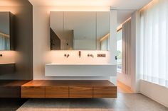 a modern bathroom with two sinks and large mirrors on the wall above it is illuminated by recessed lights