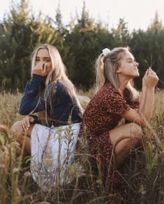 two women sitting in tall grass with trees in the background