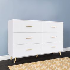 a white dresser sitting on top of a hard wood floor next to a blue wall