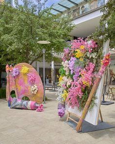 an easel with flowers on display in front of a building