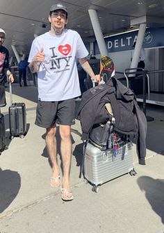 a man is walking with his luggage at the airport while wearing a t - shirt that says i love ny