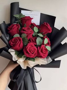 a bouquet of red roses wrapped in black paper