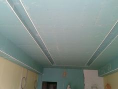 an empty room with blue walls and peeling paint on the ceiling is seen in this image