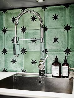 a kitchen sink under a faucet next to a green wall with black stars on it