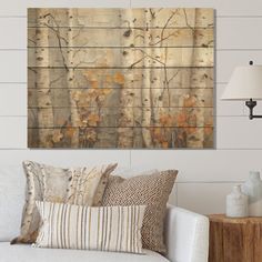 a living room scene with focus on the couch and wall art that has birch trees painted on it