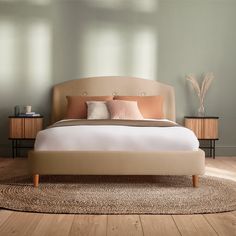 a large bed sitting on top of a wooden floor next to a wall with windows