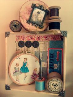 some sewing supplies are sitting on a shelf with buttons and spools in it