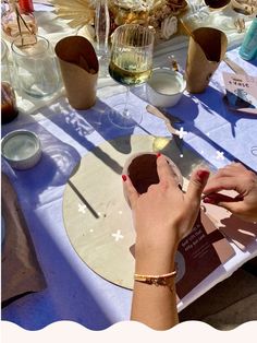 a woman is decorating a plate at a table with wine glasses and other items