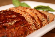 meatloaf on a plate with sauce and garnished with green leaves, ready to be eaten