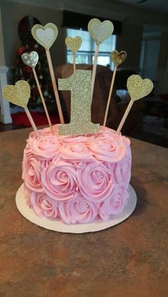 a pink and gold cake with hearts on top