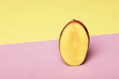 an apple cut in half on a pink and yellow background