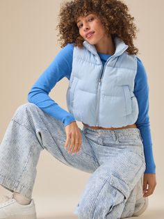 This vest features a cropped length, perfect for layering over your favorite tops. Ideal for transitional weather, it effortlessly adds a chic touch to any outfit. Light Blue Puffer Vest Outfit, Cropped Cotton Vest For Fall, Casual Stretch Crop Top For Winter, Cotton Vest For Layering In Spring, Spring Cotton Vest For Layering, Cotton Vest For Spring Layering, Casual Cotton Puffer Vest, Casual Cropped Vest Crop Top, Casual Slightly Cropped Tank Top For Spring