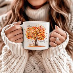 a woman is holding a coffee mug with an autumn tree on it and the words happy