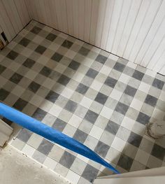 a blue pipe is in the middle of a tiled floor with white and gray tiles