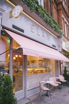 an outside view of a restaurant with pink chairs and tables in front of the window