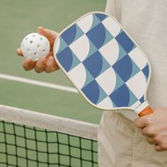 a person holding a tennis racket and ball in their hand on a court with net