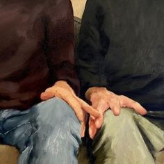 two people sitting on a couch with their hands together