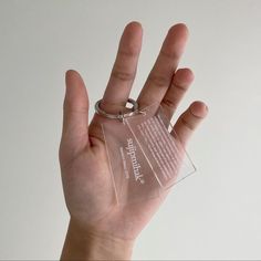 a person holding up a clear keychain in their hand