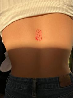 a woman's lower back with a small tattoo on her left side and the word love written in red ink