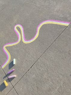 some crayons are laying on the ground next to a sidewalk with a snake drawn on it