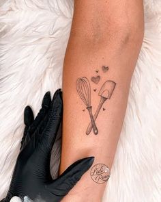 a woman with a tattoo on her arm holding a black glove next to a white fur rug