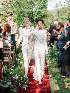 the bride and groom are walking down the red carpeted aisle as guests look on